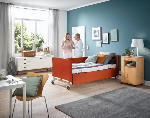 Pflegekraft spricht mit Patientin in einem modern eingerichteten Krankenzimmer.