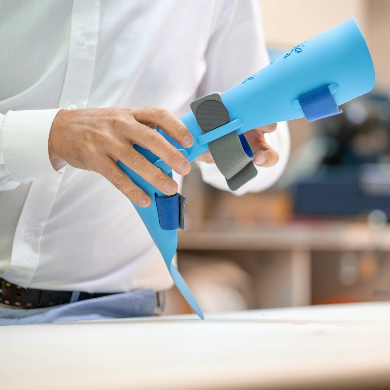 Eine Person hält ein blaues, ergonomisches Werkzeug mit grauen und blauen Griffen.