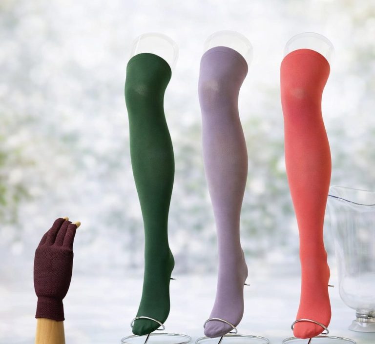 Vier lange Socken in verschiedenen Farben stehen auf Sockenspendern.