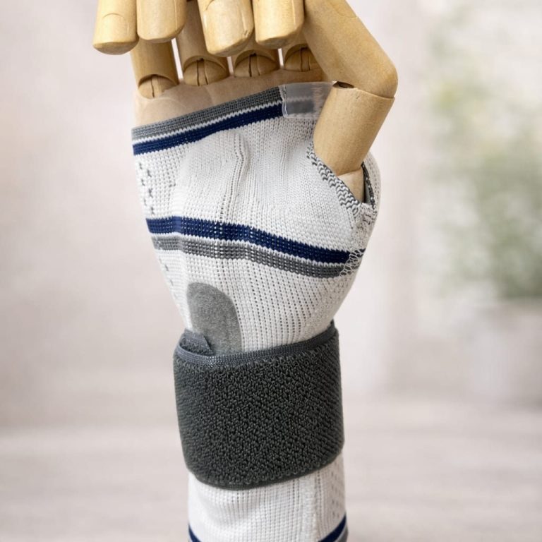 Holzmodell eines Handgelenks mit weißer Bandage und grauem Klettverschluss.