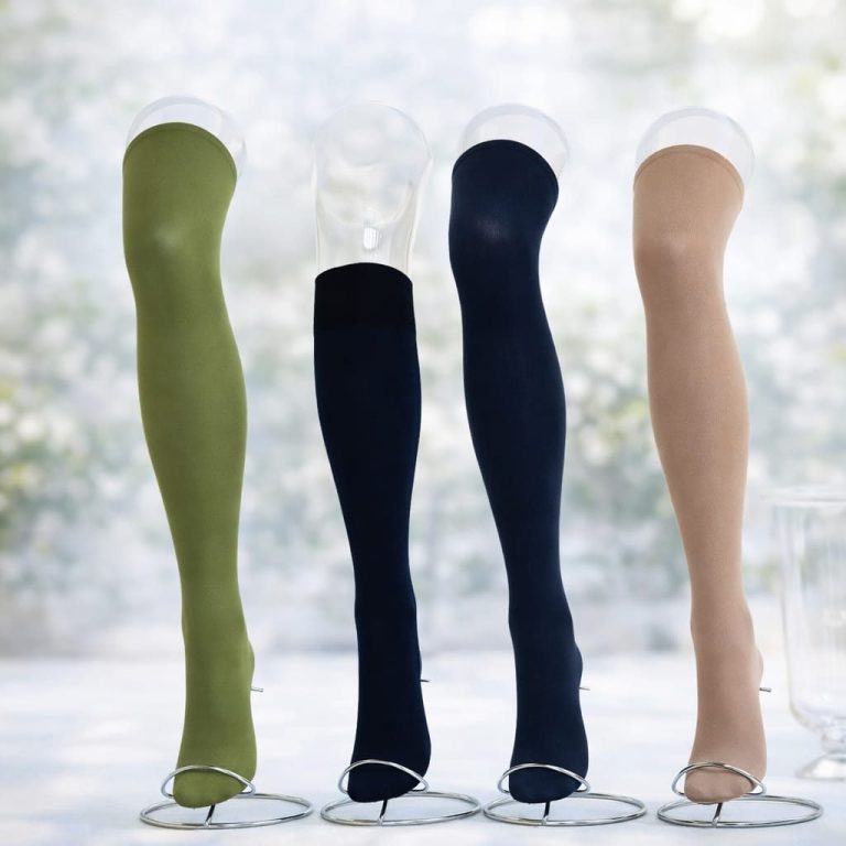 Vier unterschiedliche Strümpfe in Olive, Schwarz, Dunkelblau und Beige auf Sockelleisten.